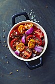 Cherry tomato salad with spices and red onions in a ceramic pot