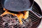 Grilled chicken being weighed down with a pan