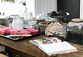 Cookery book, paper cake cases on baking tray and kitchen utensils on wooden table