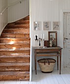 Candelabra and vintage accordion on simple table against white, wood-clad wall; rustic wooden staircase to one side