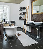 Antike frei stehende Badewanne und Waschtisch mit Goldrahmen-Spiegel in schwarz-weißem Badezimmer mit Wohnaccessoires
