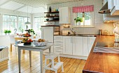 Spacious, Swedish kitchen dining room with white kitchen cabinets and dining area in conservatory-style extension