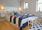 Maritimes Schlafzimmer mit blau-weiss gestreiftem Überwurf und gehäkelter 'Stars and Strips' Decke auf dem Doppelbett