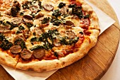 A pizza topped with wild boar sausage, braised green kale and smoked mozzarella cheese