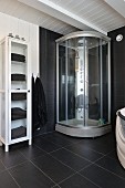 Moderne Duschkabine und Vintage Vitrinenschrank mit Handtüchern im schwarz-weissen Badezimmer eines skandinavischen Holzhauses