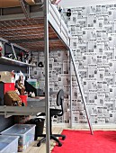 Jugend-Hochbett aus Metall mit integriertem Schreibtisch; mit den Titelblättern englischer Zeitungen tapezierte Rückwand