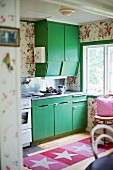 Küchenschränke mit grünen Fronten, davor Teppichläufer mit Sternenmotiven auf Holzboden