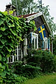 Rustikales Holzhaus mit schwedischer Fahne an der Fassade