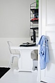 Black and white study area with white designer chair, desk and retro, wall-mounted shelves