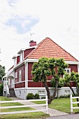 Front garden of traditional Swedish house with wooden elements painted Falu red and white
