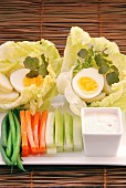 Vegetable sticks with a dip and hard-boiled eggs served on lettuce leaves