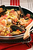 Paella with chicken, fish and seafood in a pan