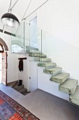 Concrete staircase with floating steps and glass balustrade in foyer