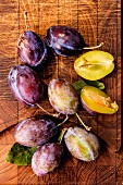 Fresh plums on a wooden board (seen from above)