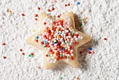 A star biscuit with colourful sprinkles in icing sugar