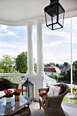 Wicker armchairs and table on roofed, old-fashioned terrace with columns