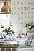 Table set with white crockery and vase of flowers in dining room with botanical wallpaper