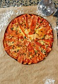 Salmon pizza on a piece of baking paper (seen from above)