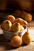 Pears in a metal bowl on a wooden surface