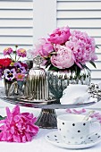 Romantic arrangement of peonies & silver accessories on table