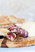 Italian salami and pecorino on a wooden board in front of a stone wall