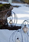 Baubles made from metal rings with silver Christmas baubles hanging from tree trunk in snowy landscape