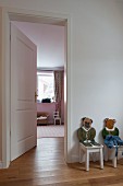 Kinderstühle mit Tiermotiv als Rückenlehne neben offener Tür zum Kinderzimmer