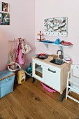 Kinderküche und blau lackierte Wandkonsole an rosa getönter Wand in Kinderzimmerecke