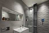 Designer Badezimmer - Waschbecken vor gefliester Wand, darüber Nische mit Spiegel, seitlich im Duschbereich 3D-Fliesen an der Wand