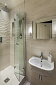 Waschbecken und Spiegel an gefliester Wand, teilweise mit dreidimensionaler Struktur, seitlich Duschbereich