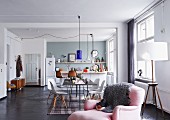 Offener Wohnraum mit Küche, Essplatz mit Klassikerstühlen und rosa Polstersessel im Vordergrund