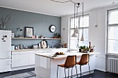 Counter with retro bar stools in simple kitchen with accent wall painted grey