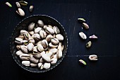 Pistachios in a silver bowl on a dark surface