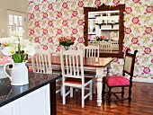 Dining room with floral wallpaper and antique chair with pink seat cushion