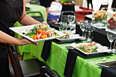 A waitress bringing Nicoise salad to a table