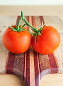 Two vine tomatoes on a chopping board