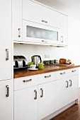 White fronts with robust, U-shaped handles and exotic wood work surface in modern fitted kitchen