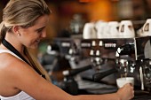 Junge Kellnerin bereitet Kaffee im Kaffeehaus zu