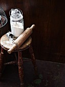 Flour and a rolling pin on a rustic wooden stool