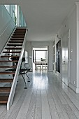 Open-plan hallway with white-stained wooden floor and staircase to one side in contemporary penthouse apartment