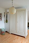 White-painted wardrobe and locker used as partition behind brightly painted paper lampshade