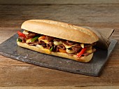 A steak sandwich with red and yellow peppers