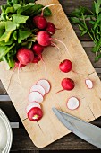 Radishes, partially sliced, on a chopping board