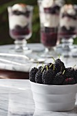 A bowl of fresh mulberries with mulberry parfait in the background