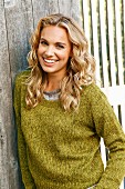 A young blonde woman wearing a green knitted jumper