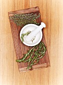 A mortar with fresh herbs on a wooden board (seen from above)