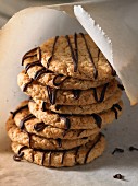 A stack of crunchy biscuits with chocolate drizzle in greaseproof paper