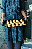 A woman holding a baking tray of gougeres (cheese profiteroles, France)