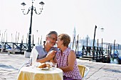 An older couple sitting at a pavement cafe, Venice, Veneto, Italy