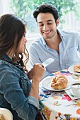 Frau fotografiert Croissants mit dem Handy im Café